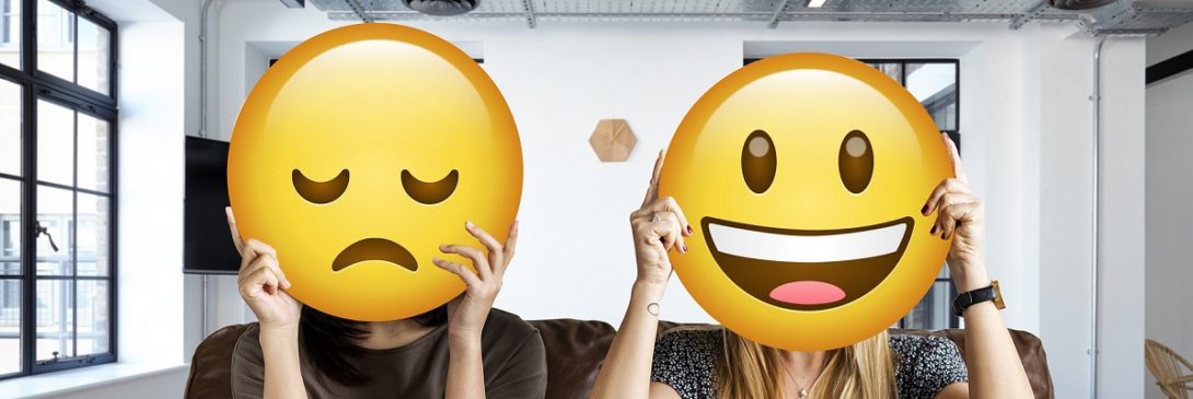 Menschen, die Emoticons hochhalten als Symbol für Mitarbeitermotivation.