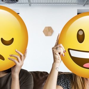 Menschen, die Emoticons hochhalten als Symbol für Mitarbeitermotivation.