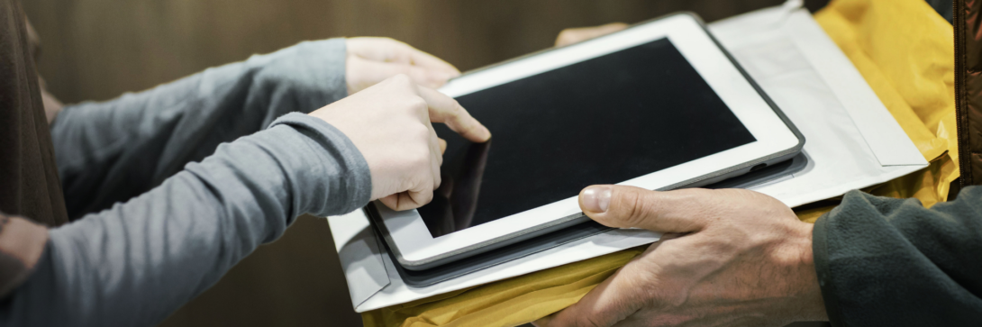 Person unterschreibt auf einem Tablet zur Bestätigung einer Lieferung – typische Anwendung einer einfachen elektronischen Signatur im Alltag.