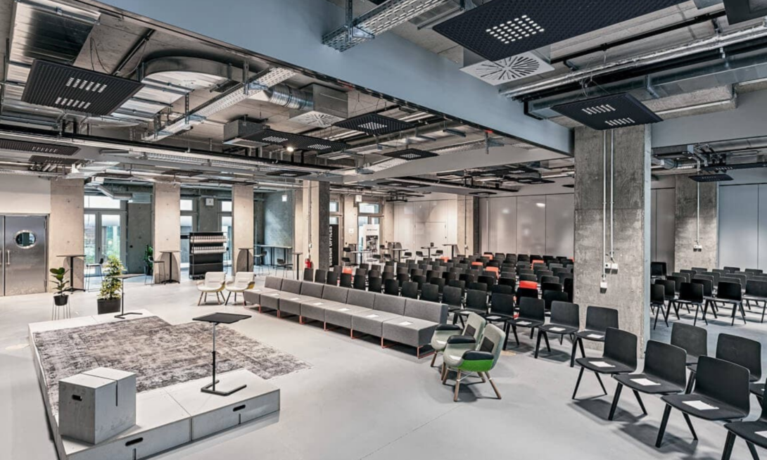 Moderner Veranstaltungsraum in den Design Offices mit Bühne und Bestuhlung – Location der d.velop Discovery Tour 2025 für Austausch und Innovation
