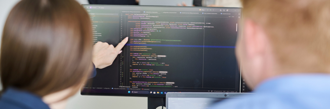 Mitarbeitende prüfen Quellcode auf einem Monitor – Anwendung der statischen Codeanalyse bei d.velop