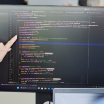 Mitarbeitende prüfen Quellcode auf einem Monitor – Anwendung der statischen Codeanalyse bei d.velop