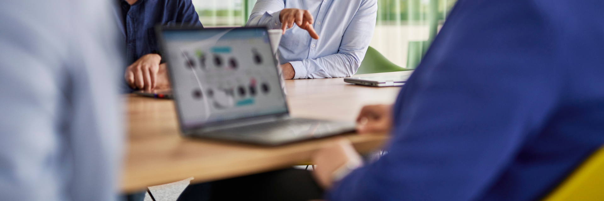 Personen im Meeting diskutieren digitale Prozesse, während auf einem Laptop ein Workflow-Diagramm zu sehen ist – symbolisiert moderne Zusammenarbeit und Digital Workplace Automation.