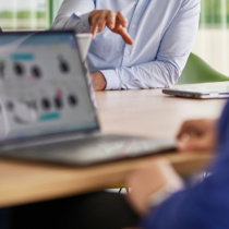 Personen im Meeting diskutieren digitale Prozesse, während auf einem Laptop ein Workflow-Diagramm zu sehen ist – symbolisiert moderne Zusammenarbeit und Digital Workplace Automation.