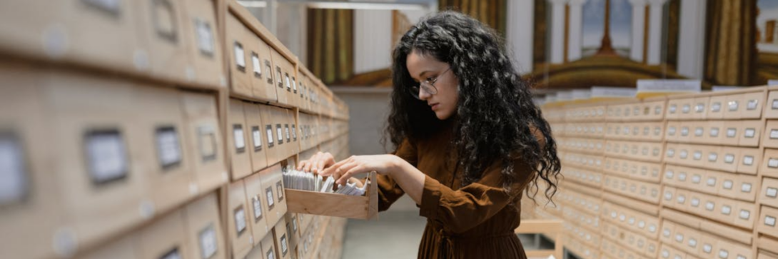 Person durchsucht Archivakten im Rahmen der Aufbewahrungsfrist in der Jugendhilfe und gesetzlicher Archivierungspflichten