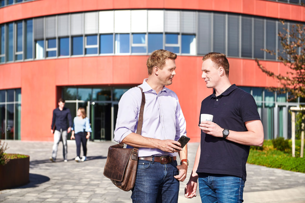 d-velop Mitarbeiter draußen mit Smartphone und Kaffee