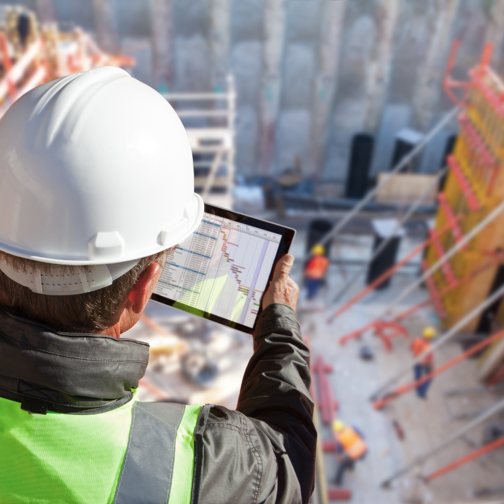 Mann steht auf einer Baustelle und schaut auf ein Tablet