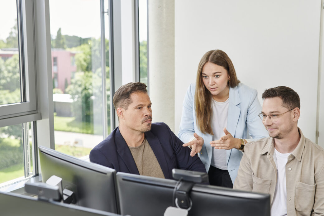 Drei Mitarbeitende von d.velop in Gespräch am Arbeitsplatz