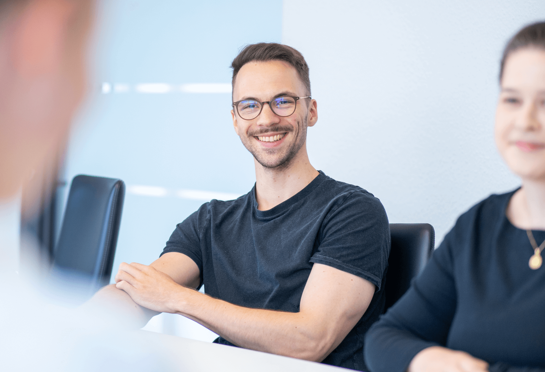 Lächelnder Mann mit Brille in einer Gesprächssituation