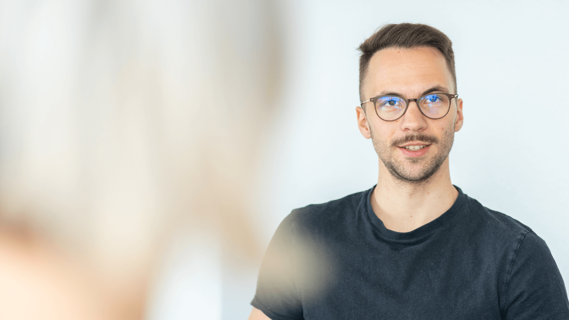 Mitarbeiter:in mit Brille in einem Gespräch