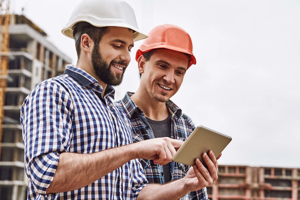 Bauarbeiter mit digitaler Bauakte auf Baustelle.