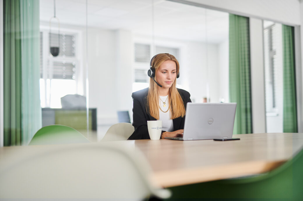 Frau, die vor dem Rechner sitzt und ein Webinar zum Thema Vertragsmanagement schaut.