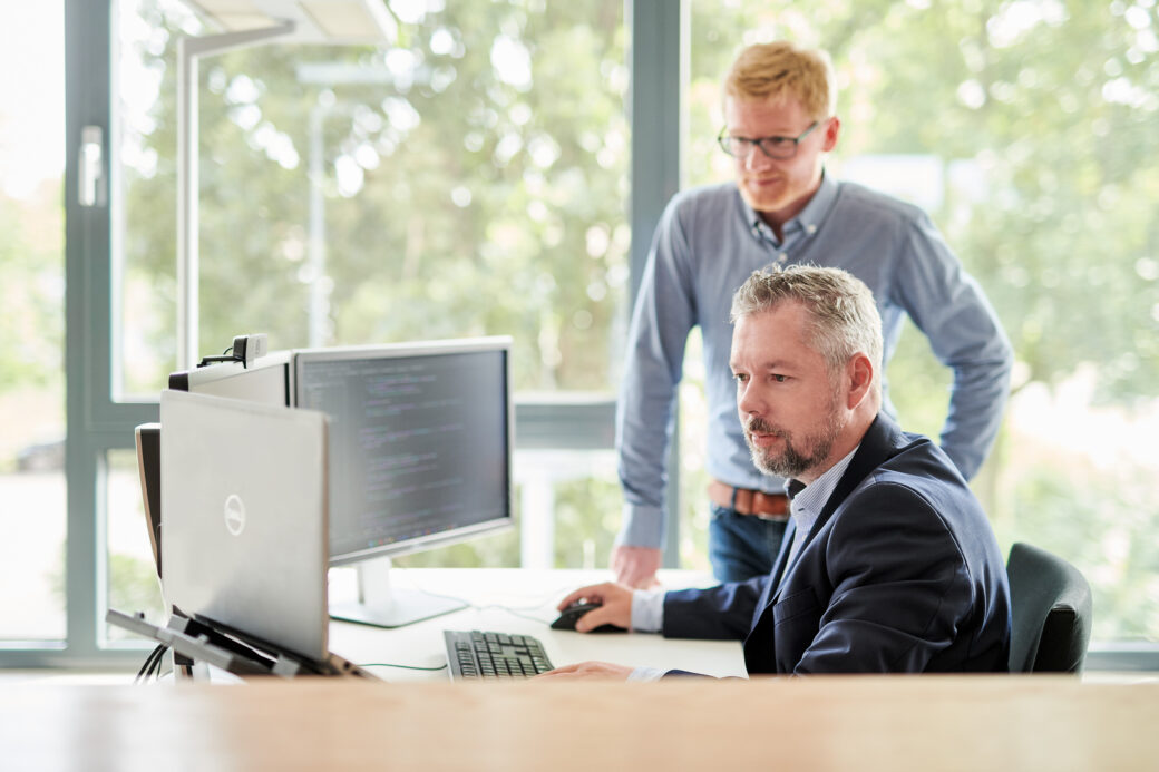 Zwei Männer schauen gemeinsam auf den Bildschirm.