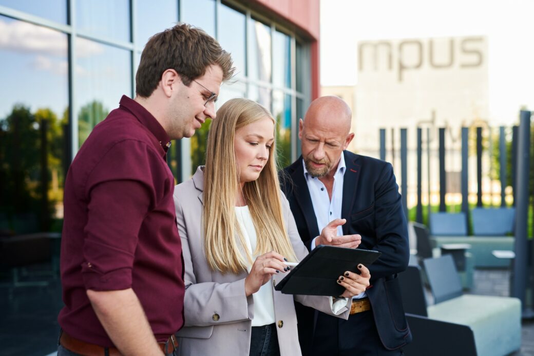 Drei Personen schauen auf ein Tablet um eine elektronische Signatur auf einem Dokument einzufügen