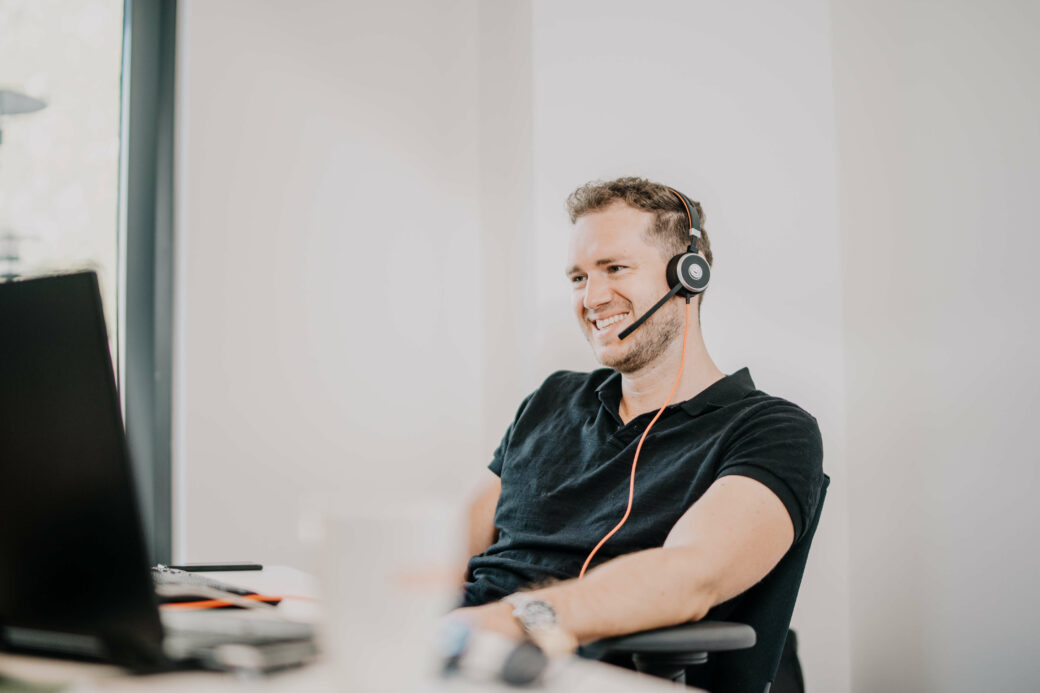 Mitarbeiter vor Laptop mit Headset